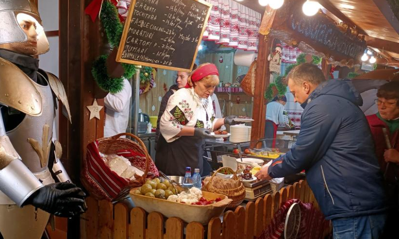 People buy snacks at the food zone during the opening day of Bucharest's Christmas fair in Constitution Square, in front of the Parliament Palace, in Bucharest, capital of Romania, Nov. 20, 2022. (Photo by Cristian Cristel/Xinhua)