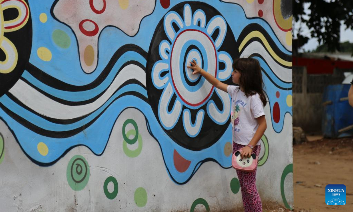 A little girl touches a painting on the wall in the slum area, Unit Seven of Maputo, Mozambique, Nov 13, 2022. Photo:Xinhua