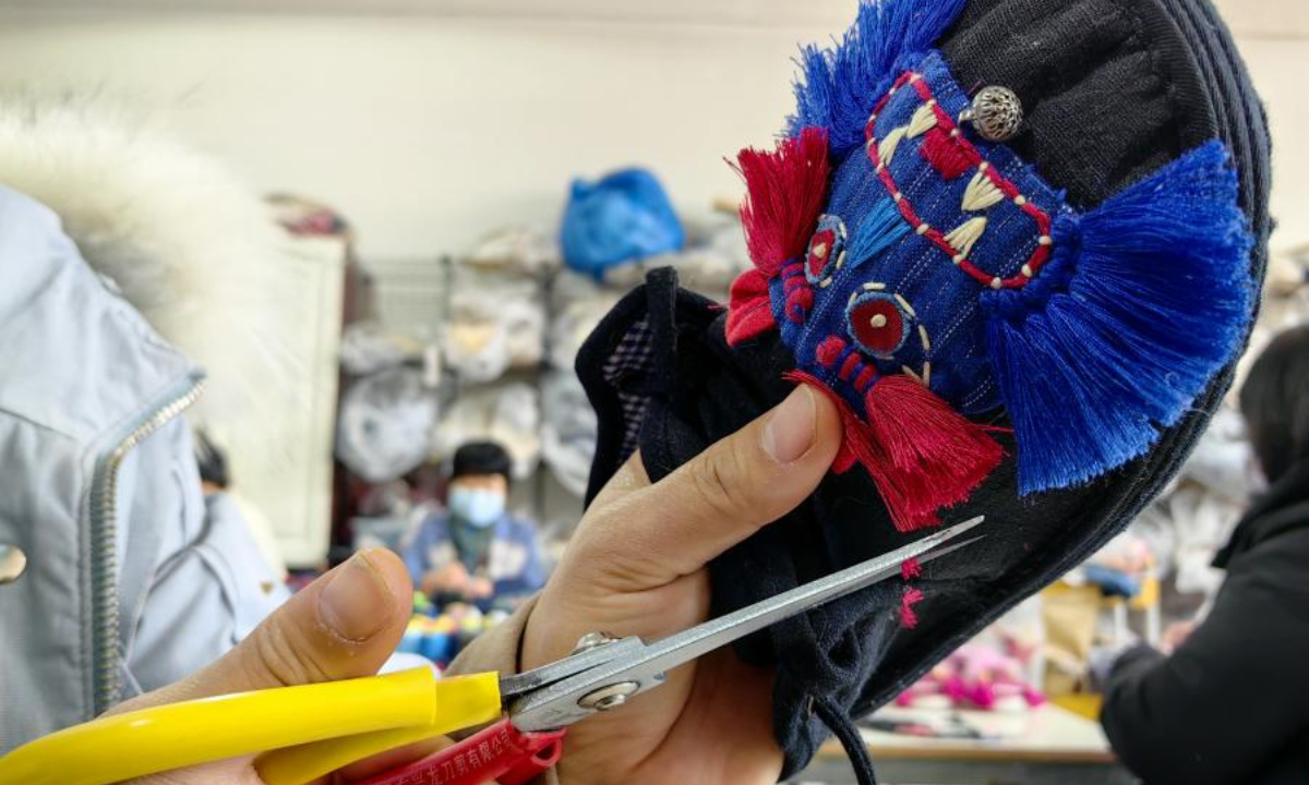 2022 年 12 月 1 日，一名妇女在中国东部山东省菏泽市的一家工厂制作中国传统布鞋。照片：中新社