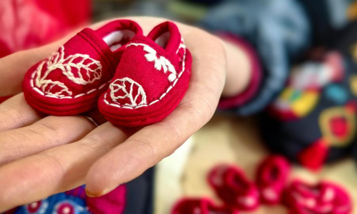 2022 年 12 月 1 日，一名妇女在中国东部山东省菏泽市的一家工厂展示一双迷你布鞋。照片：中新社