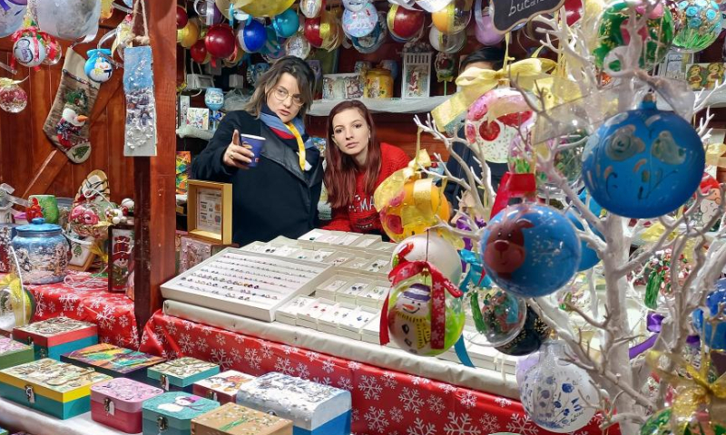 Vendors wait for customers at the gift zone during the opening day of Bucharest's Christmas fair in Constitution Square, in front of the Parliament Palace, in Bucharest, capital of Romania, Nov. 20, 2022. (Photo by Cristian Cristel/Xinhua)