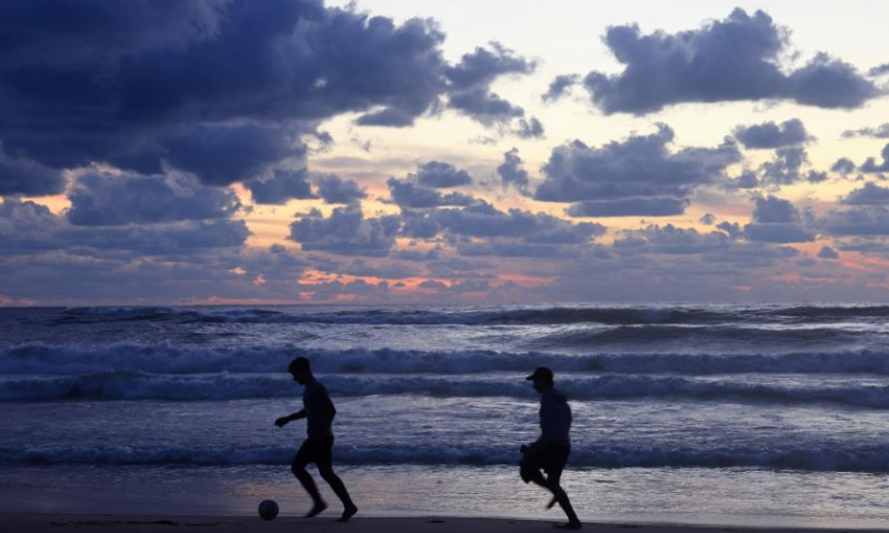 Two young men play football at sunset on the beach of the Mediterranean Sea in Beirut, Lebanon, on Nov. 26, 2022. (Xinhua/Liu Zongya)