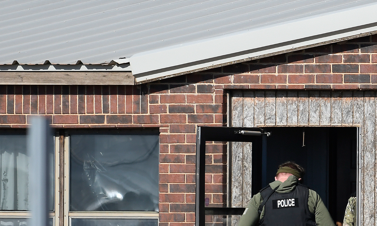 A law enforcement officer enters a residence near Lacey, Okla., in Kingfisher County, on November 21, 2022, where four people killed.