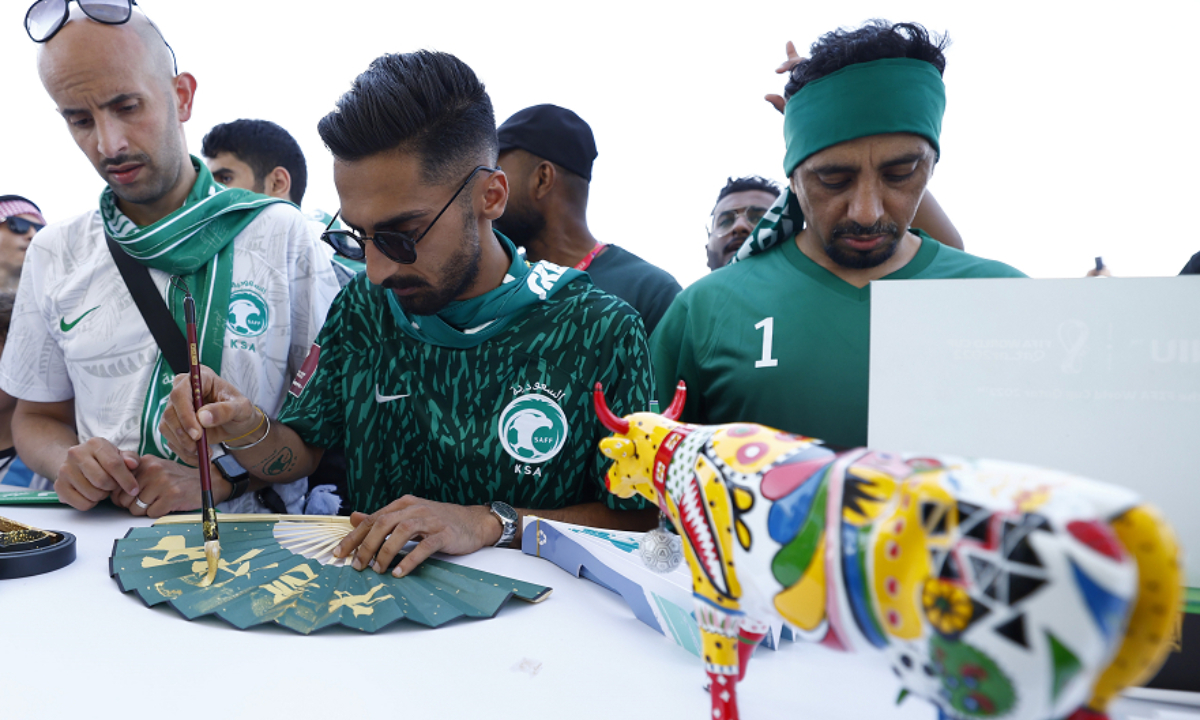 Saudi Arabian soccer fans learn to write Chinese characters at a Chinese brand stand outside Lusail Stadium in Qatar on November 22, 2022. Photo: VCG