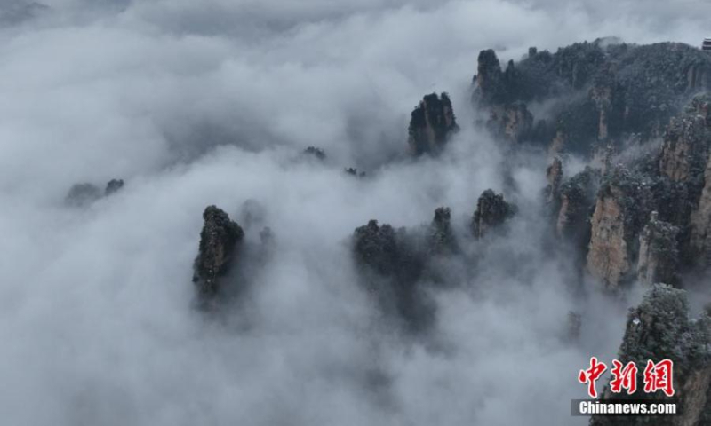 2023 年 1 月 1 日，中国中部湖南省张家界天子山风景区，雾霭覆盖的阿凡达山峰隐藏在云海中。（照片：中新社/张洪涛）
