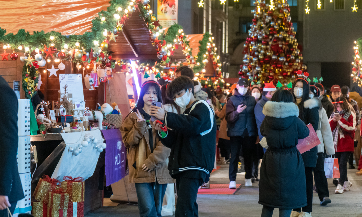Visitors take pictures and enjoy food at a market in Nanjing Pedestrian Road, a main shopping area in Shanghai on December 15, 2022. Photo: Xinhua