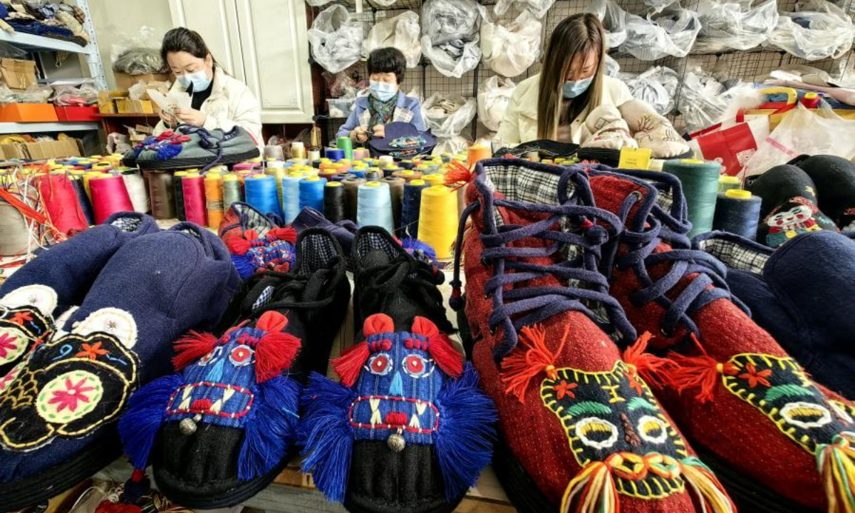 2022 年 12 月 1 日，中国东部山东省菏泽市的一家工厂，女人们正在制作中国传统布鞋。照片：中新社