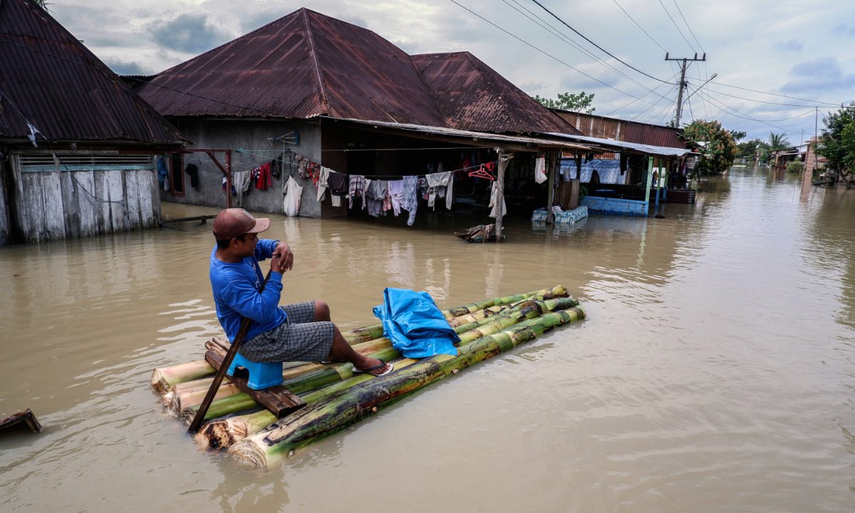 A man drives a makeshift boat used to evacuate villagers after flood inundated their houses in Sei Rampah Village in Serdang Bedagai, Indonesia on December 13, 2022. Photo: VCG