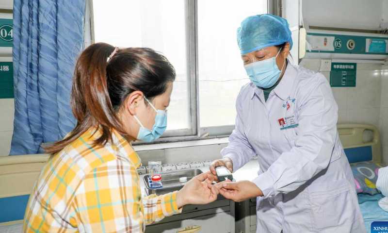 Nursing practitioner Zhang Zhiping (R) measures a patient's blood sugar level at the Workers' Hospital of Tengzhou, east China's Shandong Province, Nov. 17, 2022. Photo: Xinhua