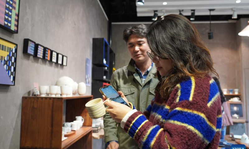 South Korean ceramist Donghyun Kang (back) introduces his artwork to a customer in his ceramic store in Taoxichuan ceramic art avenue of Jingdezhen, east China's Jiangxi Province, Oct. 26, 2022. Photo: Xinhua