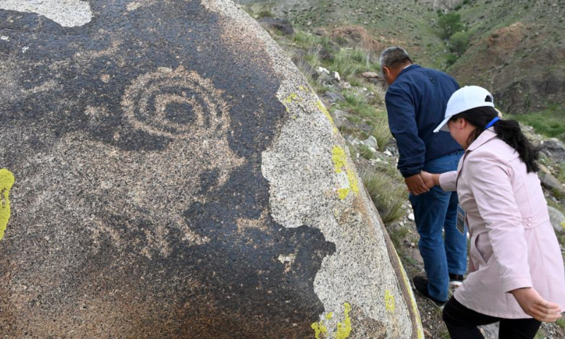 Shan Zhizheng and his wife Yuan Qin walk past a rock painting during a cultural relic site patrol in Wenquan County in the Mongolian Autonomous Prefecture of Bortala, northwest China's Xinjiang Uygur Autonomous Region, July 30, 2022. (Xinhua/Hao Jianwei)