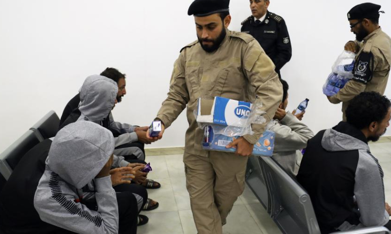 People distribute drinks to illegal migrants at the Deportation Office of the Anti-illegal Immigration Department in Tripoli, Libya, on Nov. 24, 2022. The Libyan Anti-illegal Immigration Department on Thursday deported more than 200 illegal migrants to their countries of origin. (Photo by Hamza Turkia/Xinhua)