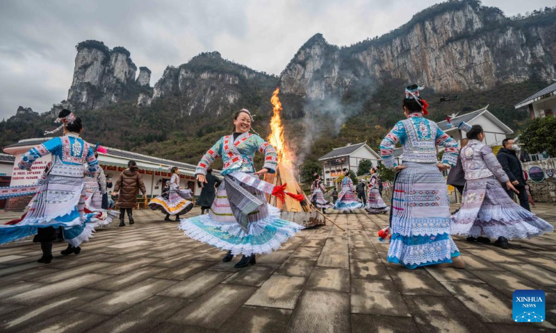 Tourists dance with people of Miao ethnic group in Huawu Village of Xinren Miao Township, Qianxi City, southwest China's Guizhou Province, Jan. 2, 2023. The three-day New Year holiday witnessed a strong recovery in tourism, catering and retail sales across the country. (Photo by Luo Dafu/Xinhua)