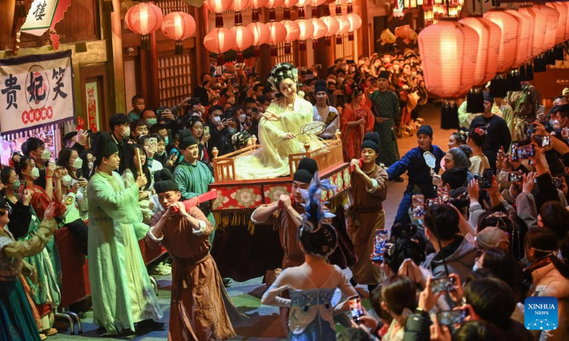 Tourists watch a performance at a theme community of Tang Dynasty in Xi'an, northwest China's Shaanxi Province, Dec. 31, 2022. The three-day New Year holiday witnessed a strong recovery in tourism, catering and retail sales across the country. (Photo by Zou Jingyi/Xinhua)