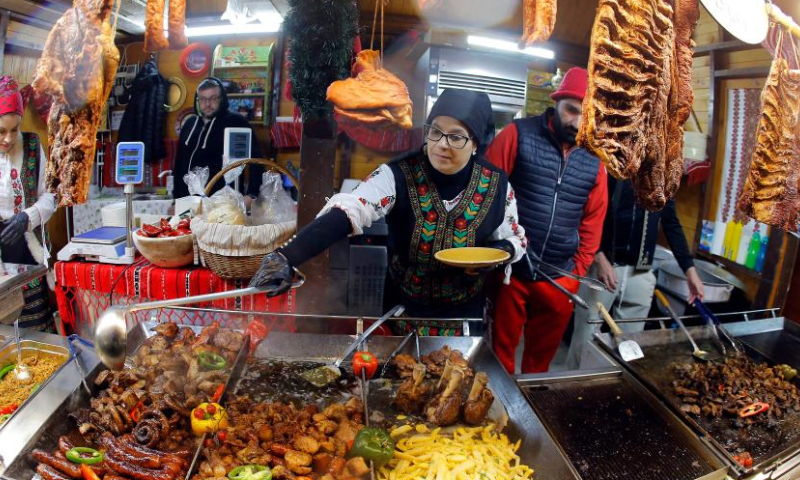 Vendors wait for customers at the food zone during the opening day of Bucharest's Christmas fair in Constitution Square, in front of the Parliament Palace, in Bucharest, capital of Romania, Nov. 20, 2022. (Photo by Cristian Cristel/Xinhua)