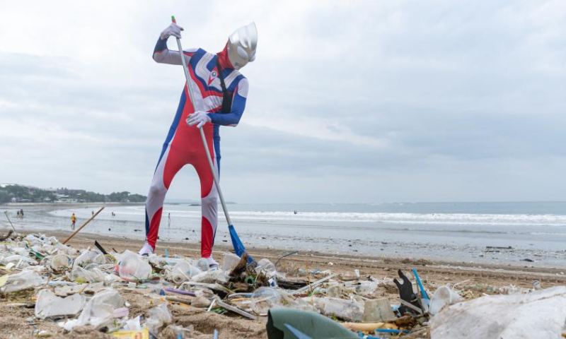 A volunteer wearing a costume of the Japanese fictional superhero Ultraman cleans trash at Kuta Beach in Bali, Indonesia, Dec. 30, 2022. Photo: Xinhua