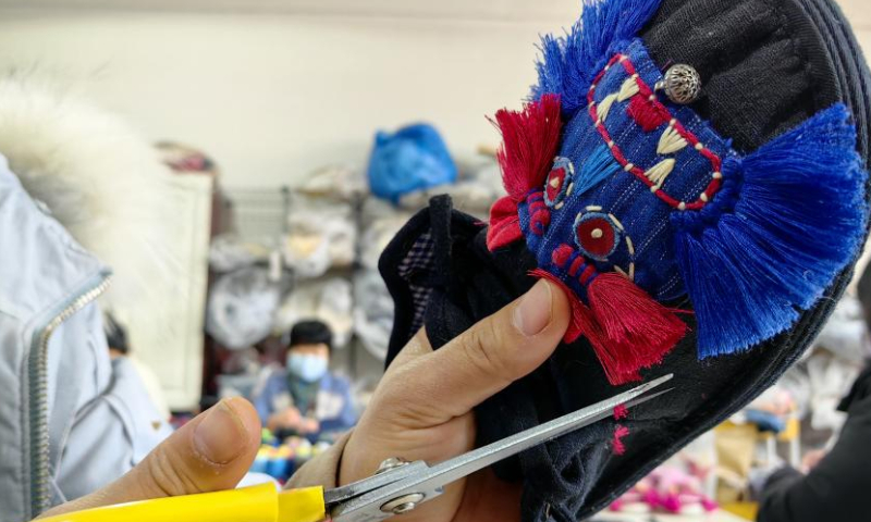 2022 年 12 月 1 日，一名妇女在中国东部山东省菏泽市的一家工厂制作中国传统布鞋。（图片来源：中新社/高玉华）