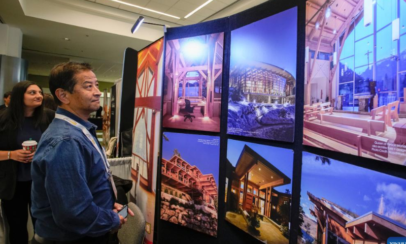 Event attendees look at wood construction images at an exhibition hall during the Wood Solutions Conference in Vancouver, British Columbia, Canada, on Nov. 15, 2022. Photo: Xinhua
