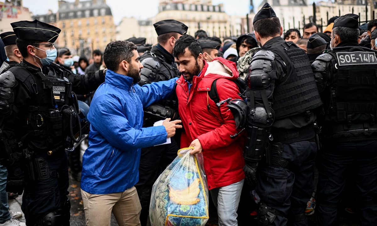 Cordoned by French Gendarmes mobile riot unit, migrants queue to embark buses for temporary shelter during the evacuation of their makeshift camp gathering hundreds, mostly Afghan, in Paris on November 17, 2022. Photo: AFP