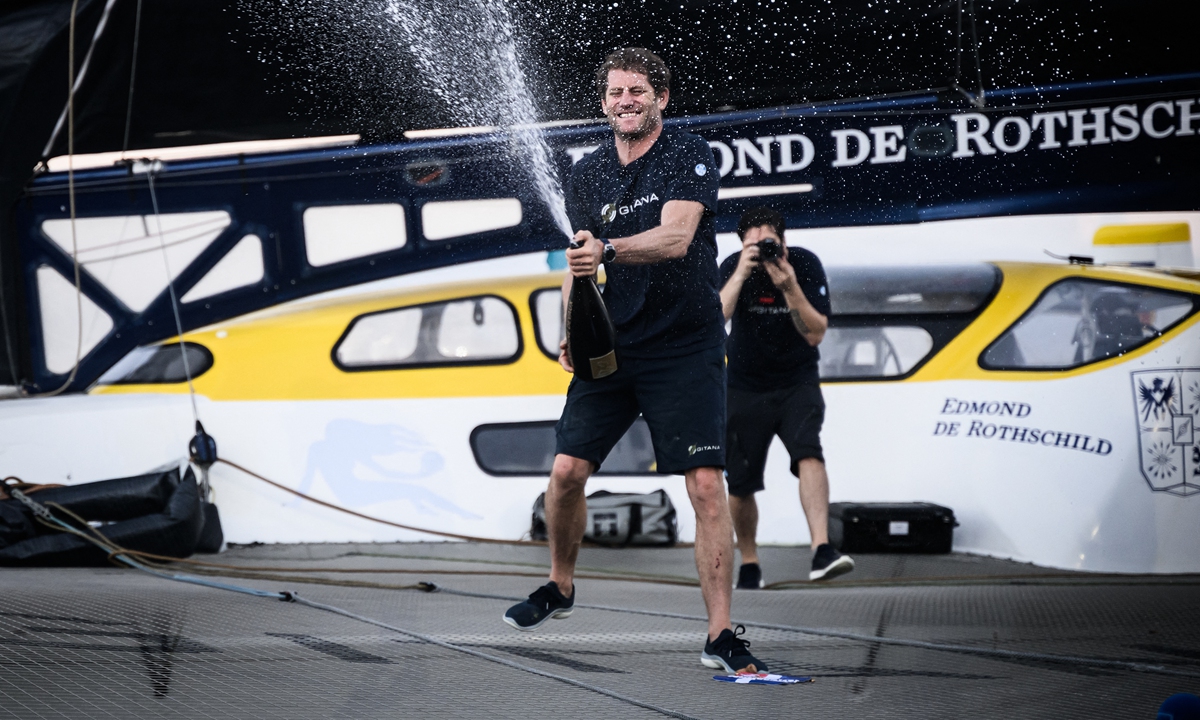 French skipper Charles Caudrelier celebrates with champagne onboard his Ultim multihull Gitana - <em>Edmond de Rothschild</em>, after winning the Route du Rhum solo sailing race, on November 16, 2022, in Pointe-a-Pitre in the French west indies. Photo: AFP