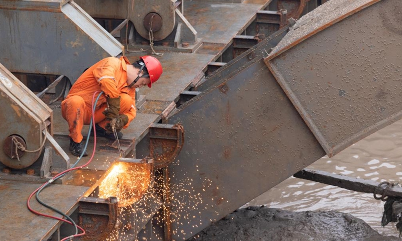 A worker fixes the body of the Yangtze No. 2 Ancient Shipwreck at the salvage operation site in Shanghai, east China, on Nov. 21, 2022. An ancient shipwreck, one of the largest and best-preserved wooden shipwrecks discovered underwater in China to date, was lifted out of waters in Shanghai early Monday.