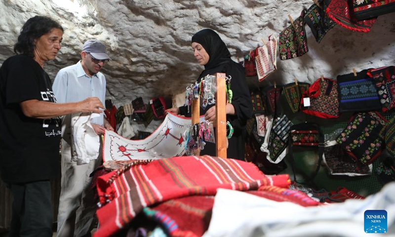 People visit an exhibition for Palestinian homemade products inside an archaeological cave, in Khirbet Susiya, south of the West Bank city of Hebron, on Oct. 8, 2022.(Photo by Mamoun Wazwaz/Xinhua)
