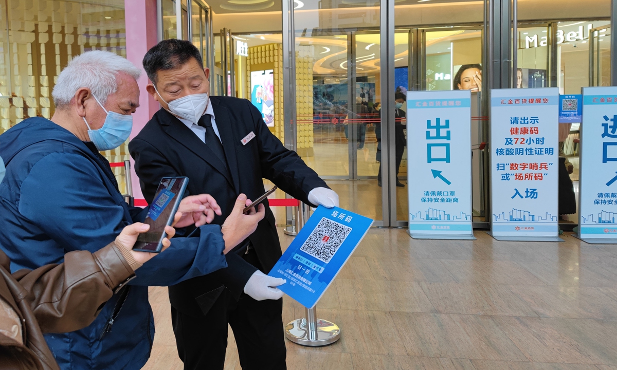 Residents scan a QR code to confirm their negative nucleic acid results before entering a shopping mall in Shanghai on Monday. Photo: VCG