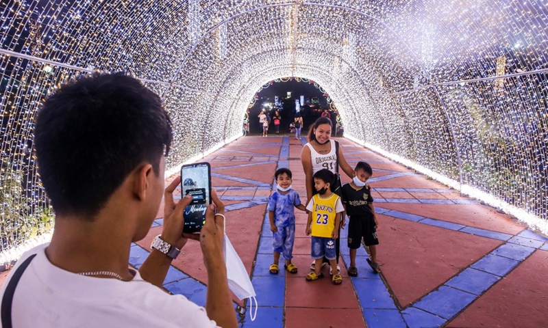 People pose for a photo inside a Christmas light tunnel at the Quezon Memorial Circle in Quezon City, the Philippines, Nov. 28, 2022.(Photo: Xinhua)