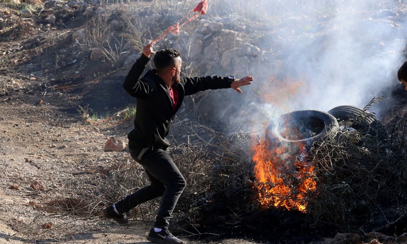 A protester uses a slingshot to hurl a stone at Israeli soldiers following a protest against the expanding of Jewish settlements in the village of Beita, south of the West Bank city of Nablus, on Nov. 18, 2022.(Photo: Xinhua)