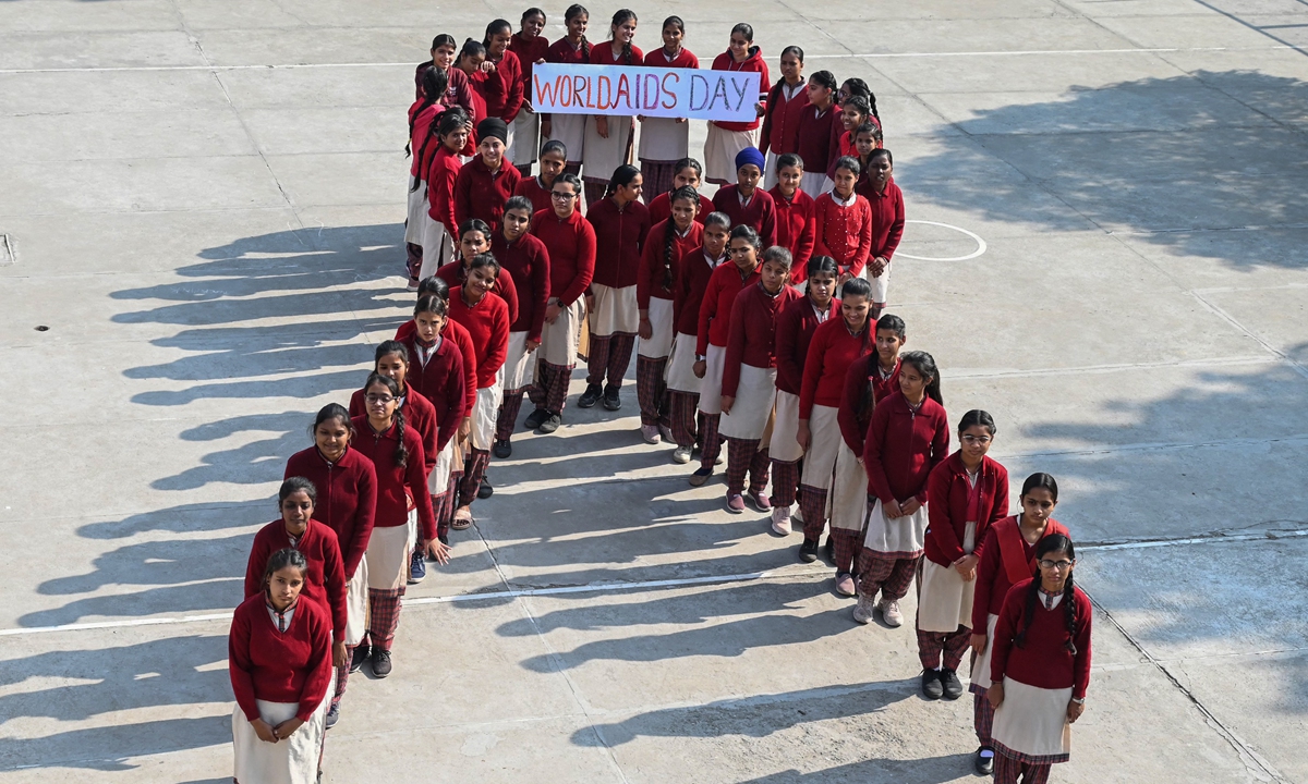 Students pose for a group photograph as they stand in the shape of a ribbon as part of an awareness event on the eve of the World AIDS Day at a Government Girls' senior high school in Amritsar, India on November 30, 2022. Photo: AFP