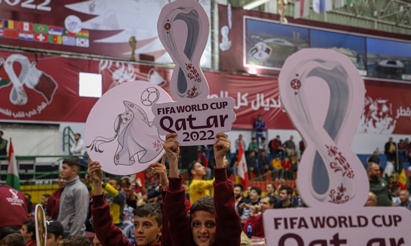A Palestinian boy holds the logo of FIFA World Cup Qatar 2022 when he is watching the opening ceremony and opening match between Qatar and Ecuador at a gymnasium in Gaza City, on Nov. 20, 2022. (Photo: Xinhua)