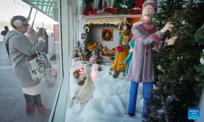A woman takes photos of vintage Christmas window displays at Canada Place in Vancouver, British Columbia, Canada, on Dec. 12, 2022. The vintage Christmas window displays are now for viewing here as part of the Christmas highlights in Vancouver.(Photo: Xinhua)