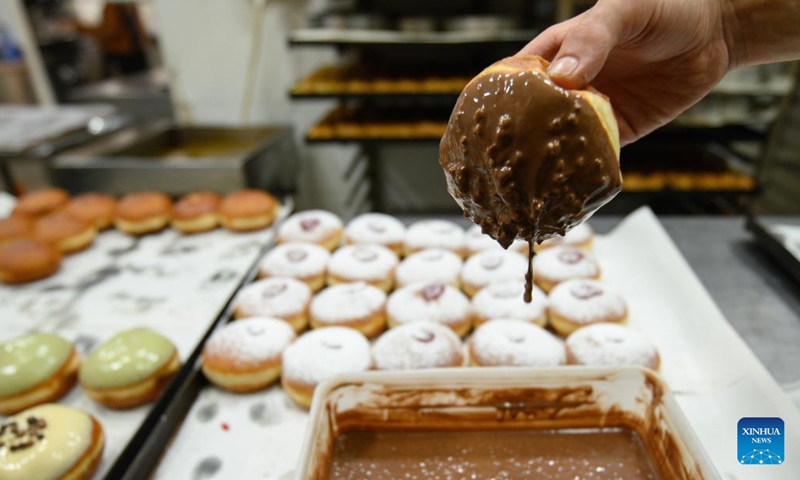 A bakery worker makes sufganiyot, round jelly donuts eaten during the Jewish festival of Hanukkah, at a bakery in Kiryat Shmona, northern Israel, on Dec. 14, 2022.(Photo: Xinhua)