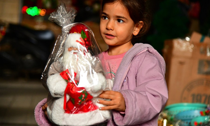 A Syrian girl hugs a Christmas decoration in Damascus, Syria, Dec. 12, 2022.(Photo: Xinhua)
