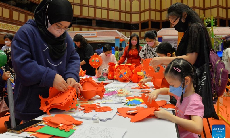 People make paper lanterns during a China Day cultural event in Bandar Seri Begawan, Brunei, on Dec. 16, 2022. The China Day cultural event, as part of the Brunei December Festival, was launched here at the International Convention Center on Friday. A series of activities showcasing Chinese cultures such as wushu, calligraphy, delicacy, and sales of Chinese goods and specialties will be staged during the three-day cultural event. (Photo by Jeffrey Wong/Xinhua)