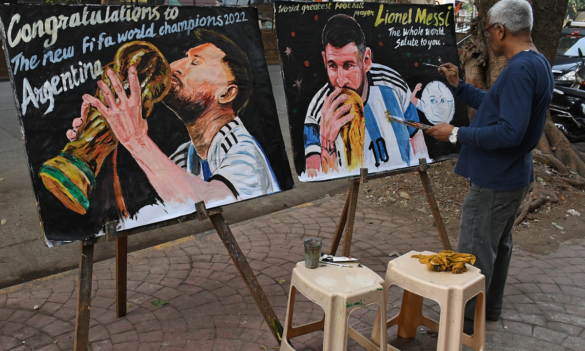An artist puts final touches to a painting of Lionel Messi kissing the World Cup Trophy, in Mumbai, India on December 19, 2022. Photo: VCG