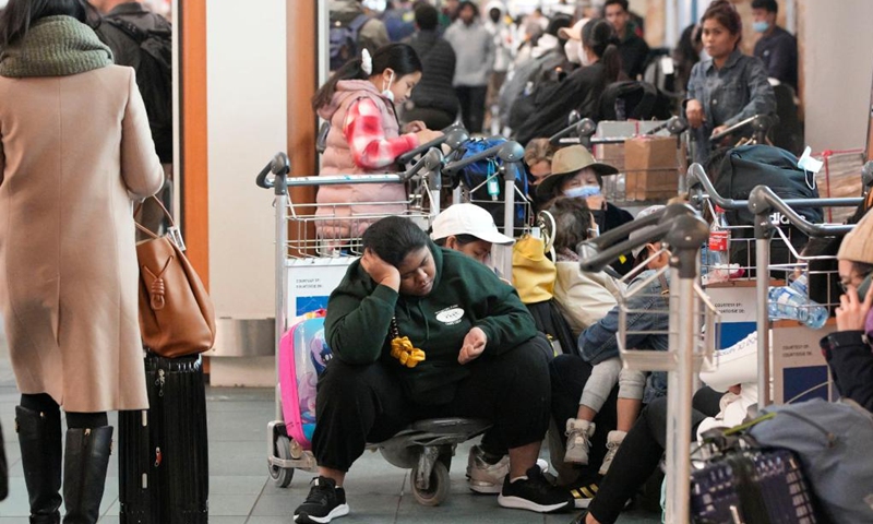 People sit on trolleys at Vancouver International Airport in Richmond, British Columbia, Canada, on Dec. 20, 2022. Thousands of travelers were stuck at the Vancouver International Airport on Tuesday as many flights were cancelled or delayed due to the snowstorm.(Photo: Xinhua)