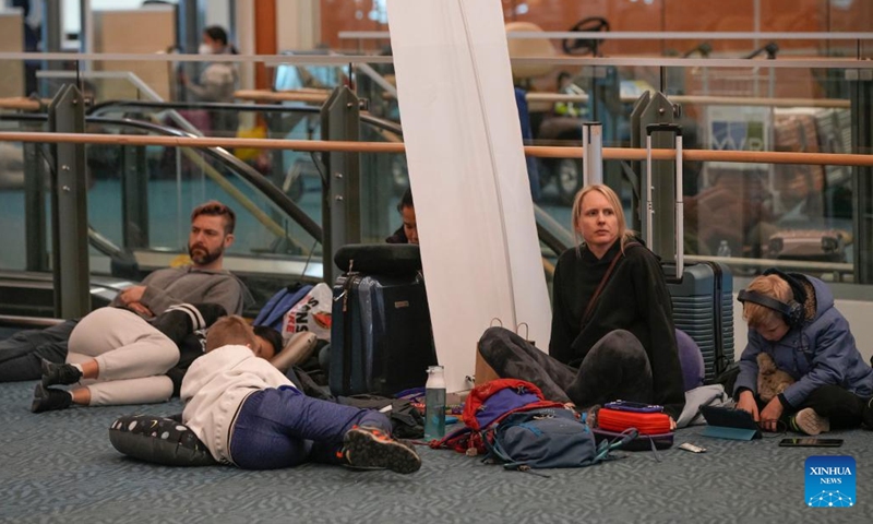 People wait on the floor at Vancouver International Airport in Richmond, British Columbia, Canada, on Dec. 20, 2022. Thousands of travelers were stuck at the Vancouver International Airport on Tuesday as many flights were cancelled or delayed due to the snowstorm.(Photo: Xinhua)