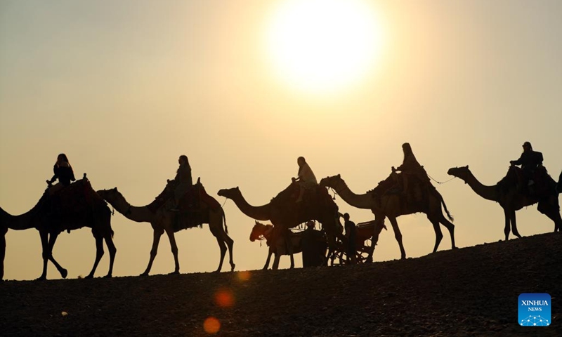 Tourists ride camels at the Giza Pyramids scenic spot in Giza, Egypt, on Dec. 22, 2022.(Photo: Xinhua)