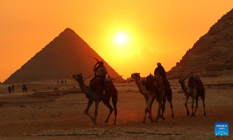 People ride camels at sunset at the Giza Pyramids scenic spot in Giza, Egypt, on Dec. 22, 2022.(Photo: Xinhua)