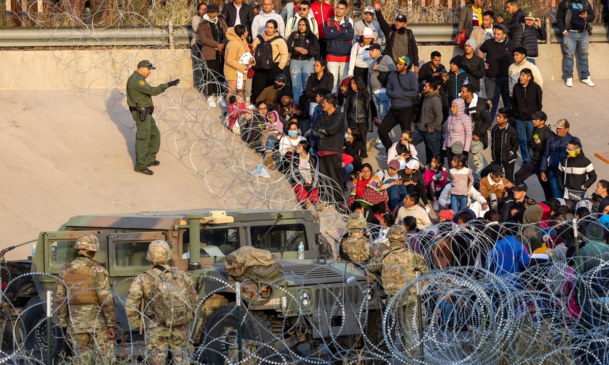 A US Border Patrol agent speaks to immigrants blocked from entering a high-traffic illegal border crossing area along Rio Grande in El Paso, Texas on December 20, 2022 as viewed from Ciudad Juarez, Mexico. Texas Governor Greg Abbott ordered 400 Texas National Guard troops and state police to the US-Mexico border in El Paso, which is under a state of emergency due to a surge of migrants crossing from Mexico into the city. Photo: VCG