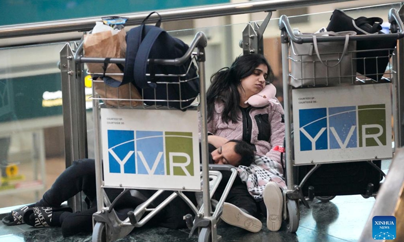 People sleep on the floor at Vancouver International Airport in Richmond, British Columbia, Canada, on Dec. 20, 2022. Thousands of travelers were stuck at the Vancouver International Airport on Tuesday as many flights were cancelled or delayed due to the snowstorm.(Photo: Xinhua)