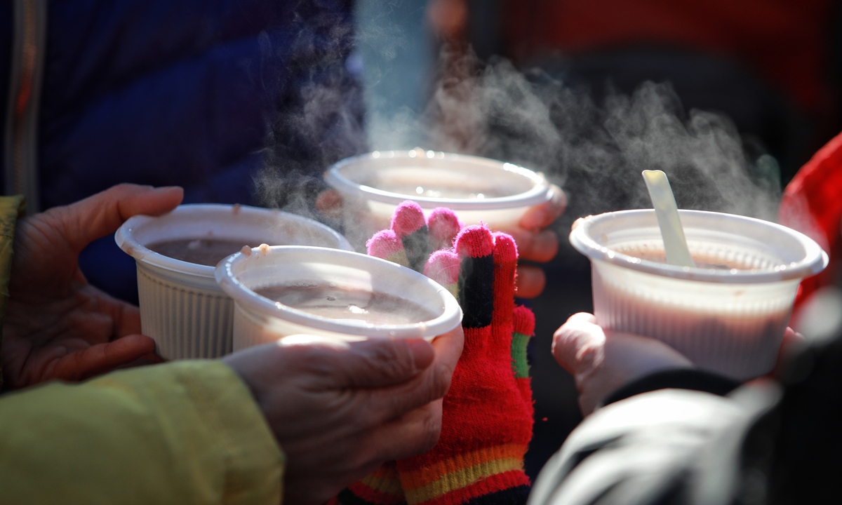 Visitors hold bowls of Laba porridge in front of the Yonghegong Lama Temple in Beijing. Photo: IC