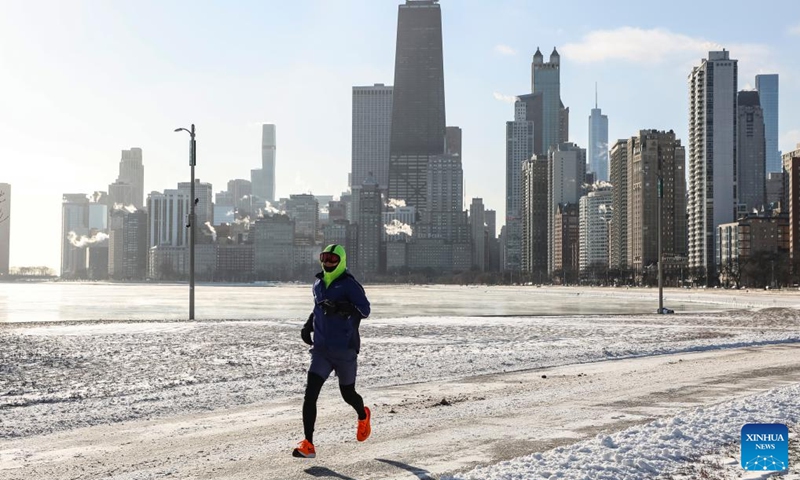A man runs by North Ave. Beach in Chicago, the United States, on Dec. 24, 2022. A strong winter storm swept through Chicago. (Photo by Joel Lerner/Xinhua)