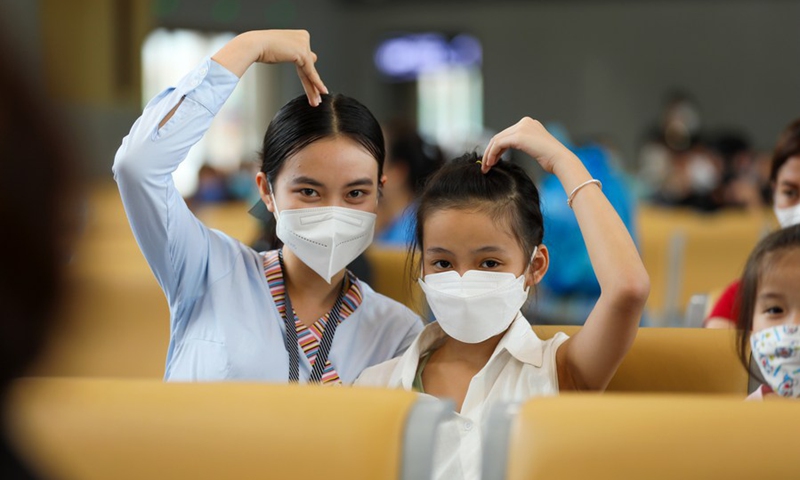 A girl and a staff member of the China-Laos Railway pose for photos in Luang Prabang, Laos, April 24, 2022. (Photo by Yang Yongquan/Xinhua)