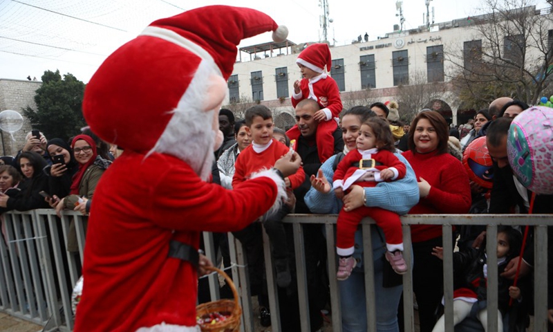 Children dressed in Christmas clothing are seen during celebrations at the Manger Square in the West Bank city of Bethlehem on Dec. 24, 2022. (Photo by Mamoun Wazwaz/Xinhua)