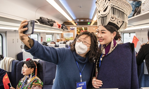 A passenger takes a photo with a woman in traditional Yi ethnic costume on the first train of the Chengdu-Kunming Railway on December 26, 2022. After more than 10 years of construction, the new railway with a total length of 915 kilometers opened to traffic, shortening the trip from 19 hours to 7.5 hours. Photo: cnsphoto