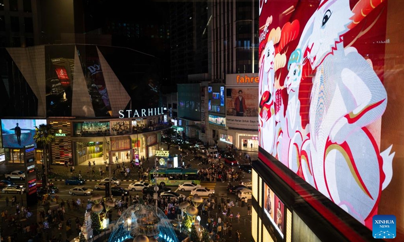 People walk outside a shopping mall as an electronic screen shows a video clip of Year of the Rabbit in Kuala Lumpur, Malaysia, Dec. 26, 2022.(Photo: Xinhua)