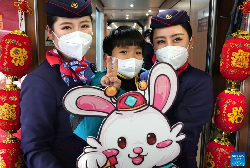 Attendants of train G2023 pose for a photo with a child on the train running from Shangqiu in central China's Henan Province to Lanzhou in northwest China's Gansu Province, Jan. 1, 2023. Various activities to celebrate the new year were held on the train G2023 as the number of the train coincides with the year of 2023. (Xinhua/Li An)
