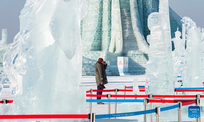 A judge looks at an ice sculpture at the Harbin Ice-Snow World theme park in Harbin, northeast China's Heilongjiang Province, Jan. 5, 2023. A competition, featuring ice sculptures with exquisite craftsmanship from 12 sculptor teams, concluded here on Saturday. (Xinhua/Xie Jianfei)